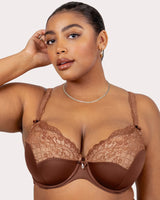 Woman wearing a brown lace bra against a plain background
