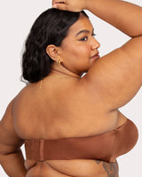 Woman wearing a brown bikini top against a plain background