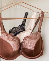 Brown lace bra on a hanger with other bras in the background